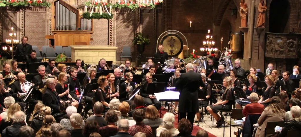 Orchestre symphonique performant dans une église, dirigé par le chef d'orchestre avec un public qui les écoute jouer devant eux.