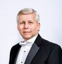 Monsieur Scott souriant face à l'objectif. Habillé d'un élégant costume blanc et noir