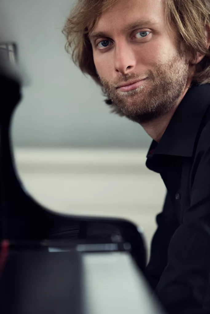 Ivo Kahanek photographed by Dusan Martincek in front of his piano, playing while smiling at the photographer.