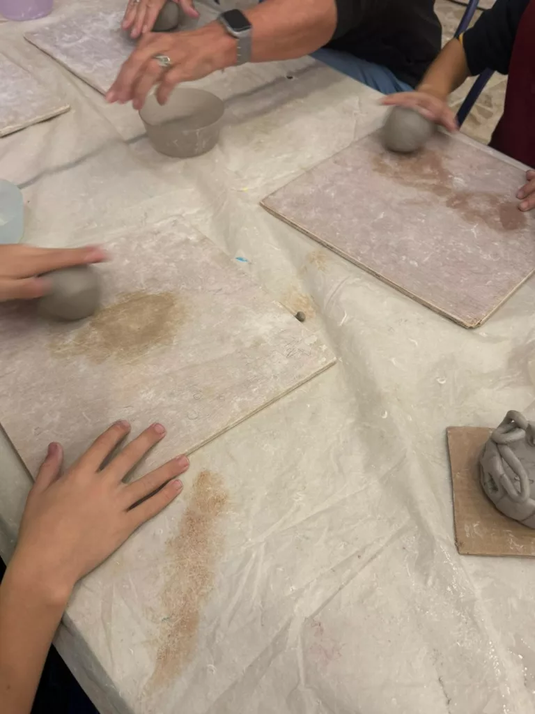 Activité avec les enfants pour qu'ils créaient des objets en argile sur le thème d'Halloween. Ils sont en train de rouler leur boule d'argile sur des plaquettes de bois.
