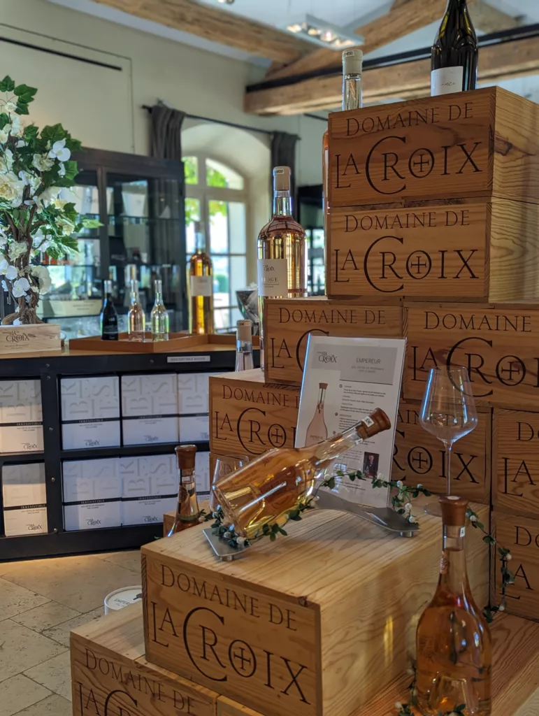 © lacroixvalmertourisme Intérieur du caveau du domaine de la croix. C'est une pyramide faite avec des caisses en bois et devant, sont exposées trois bouteilles de leur rosé haut de gamme.