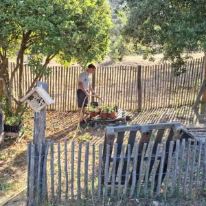 garde du PNPC en train d'arroser un petit jardin avec des cabanes à insects que les pichoun ont fait pendant les vacances.